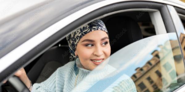 Woman in a car with an open window looking at something and smiling
