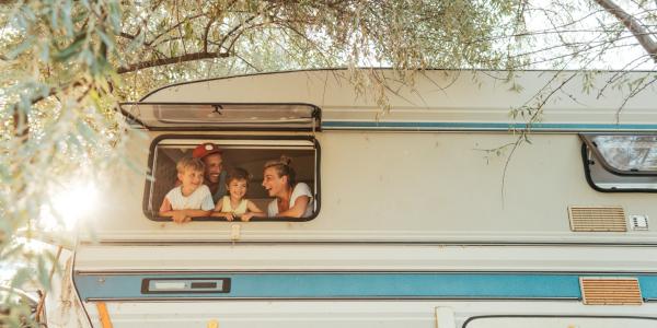 Happy family sticking their heads out of the window of their camper van during a vacation.
