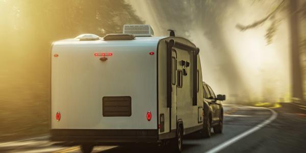 Travel trailer R.V. taking the scenic route on a road trip through foggy forests.