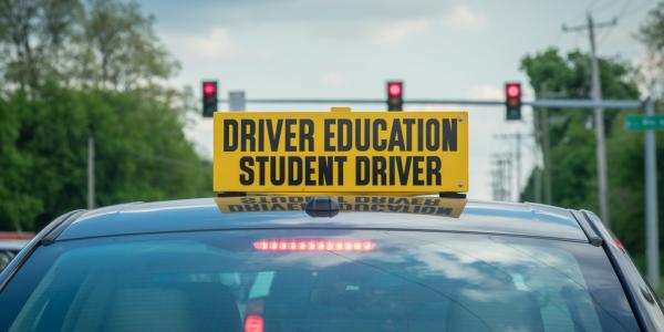 Vehicle with a sign on the roof that says "Driver Education Student Driver".